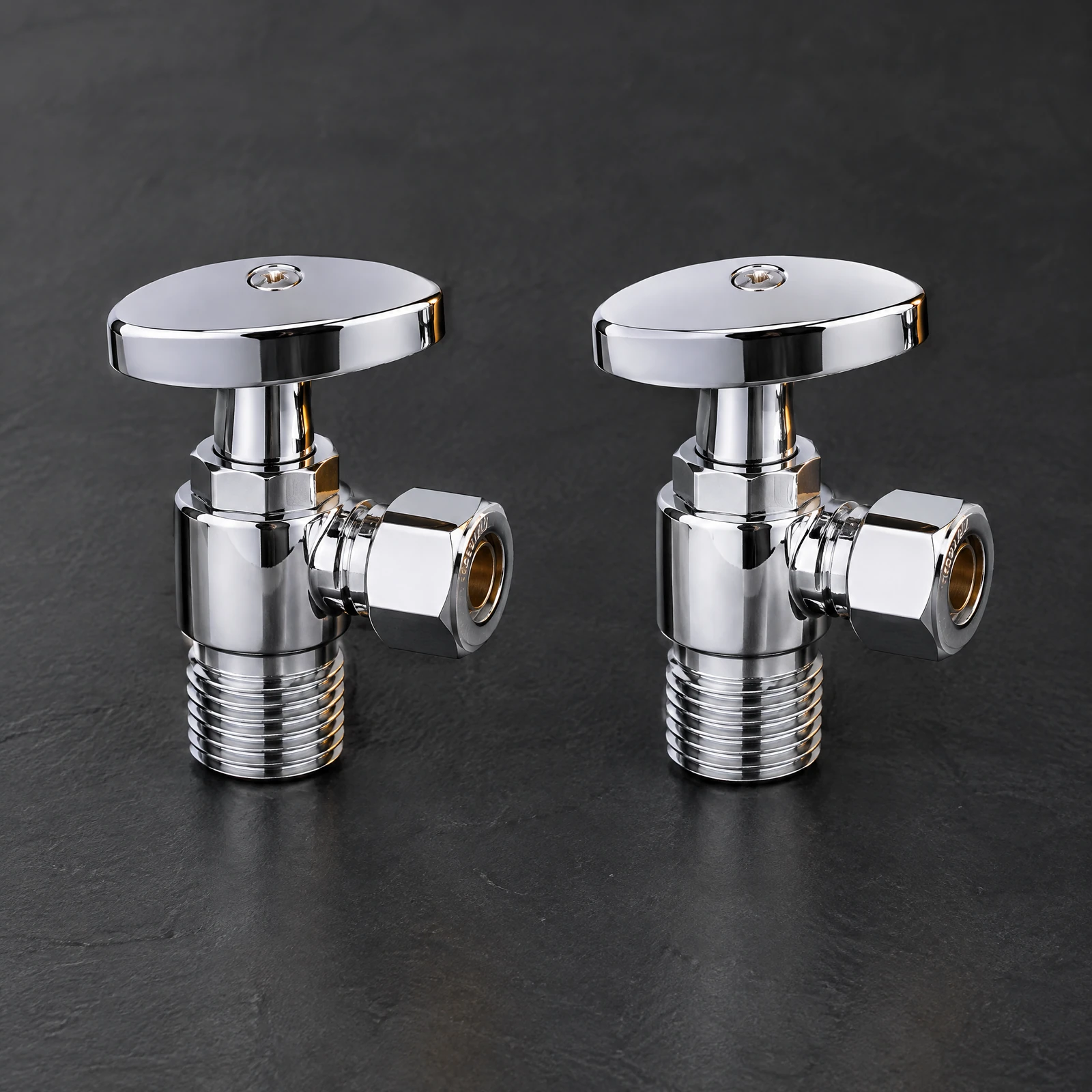 Two silver-tone angle stop valves with oval handles on a dark slate backdrop